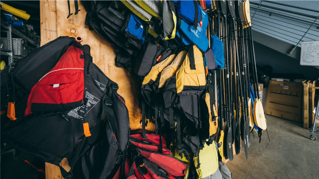 Life jackets and paddles hanging on gear storage wall